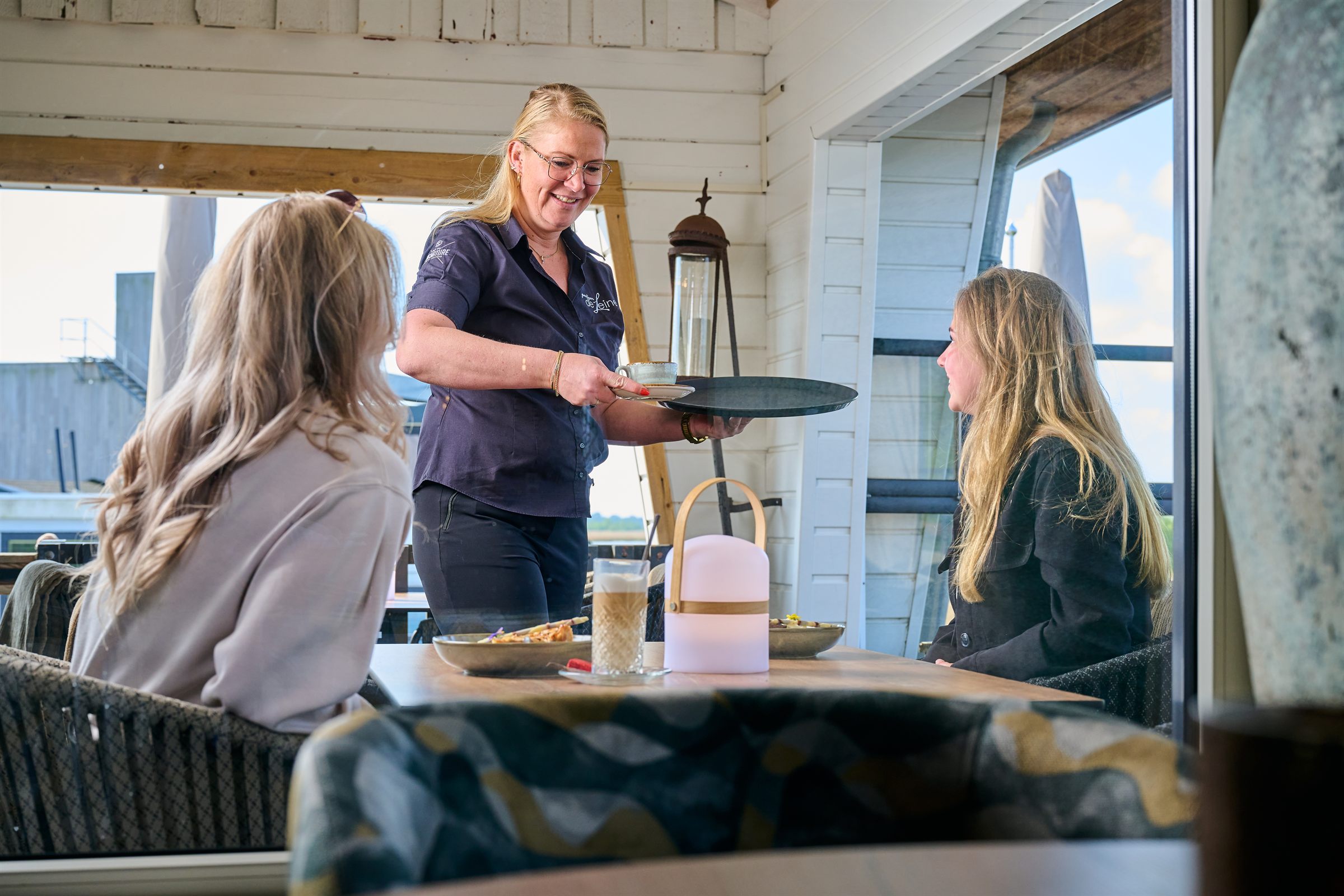 Bediening serveert aan tafel bij het raam