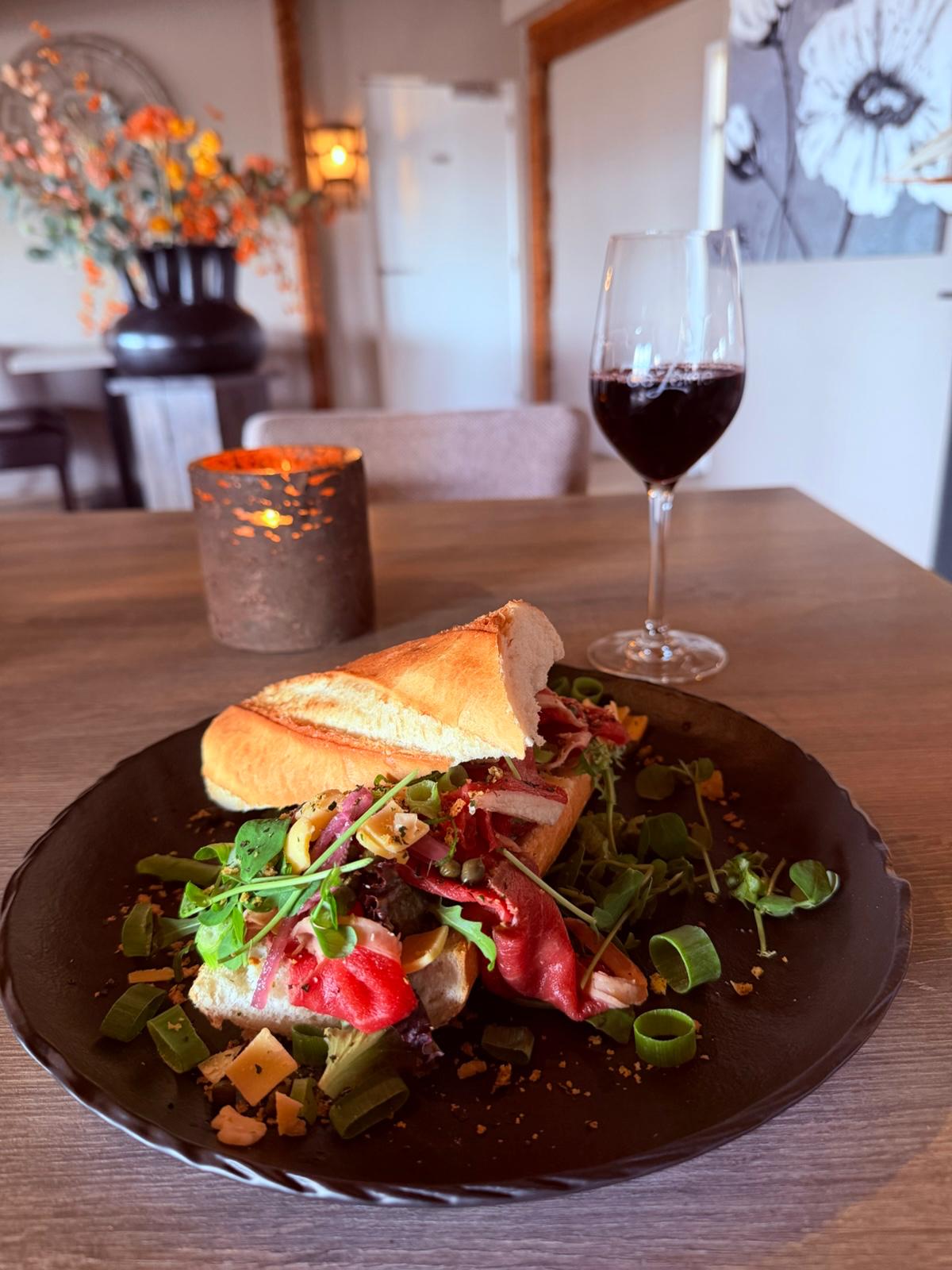 Belegd stokbrood met dungesneden rundvlees en een glas rode wijn in het restaurant