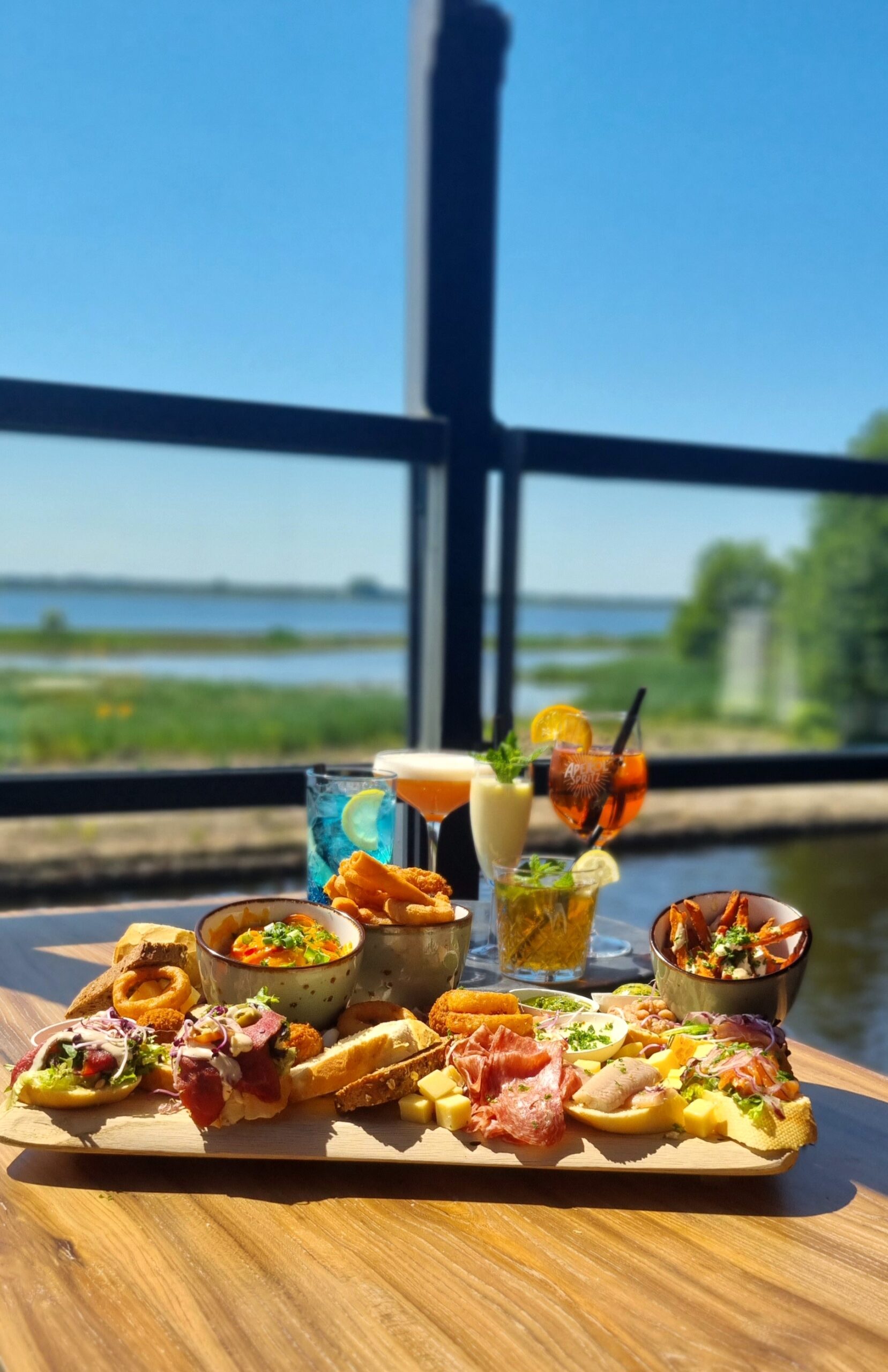 Borrelplank met cocktails op het terras aan het water