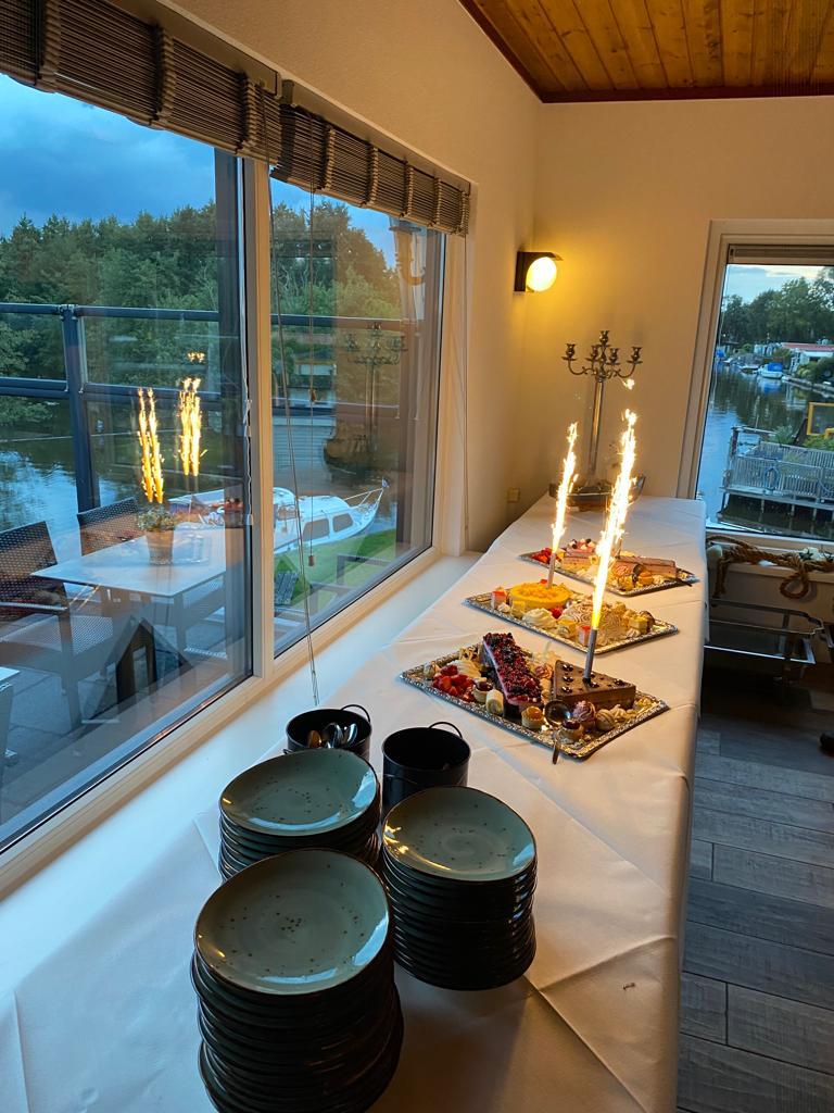 Feestelijk gedekte buffettafel met gebak en sterretjes bij het raam aan het water