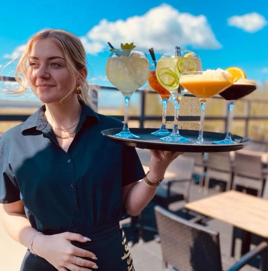 Medewerkster met een dienblad vol cocktails op het zonnige terras